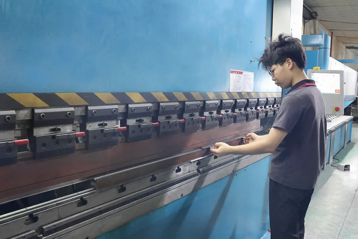 Factory worker performing precision sheet metal bending with CNC press brake