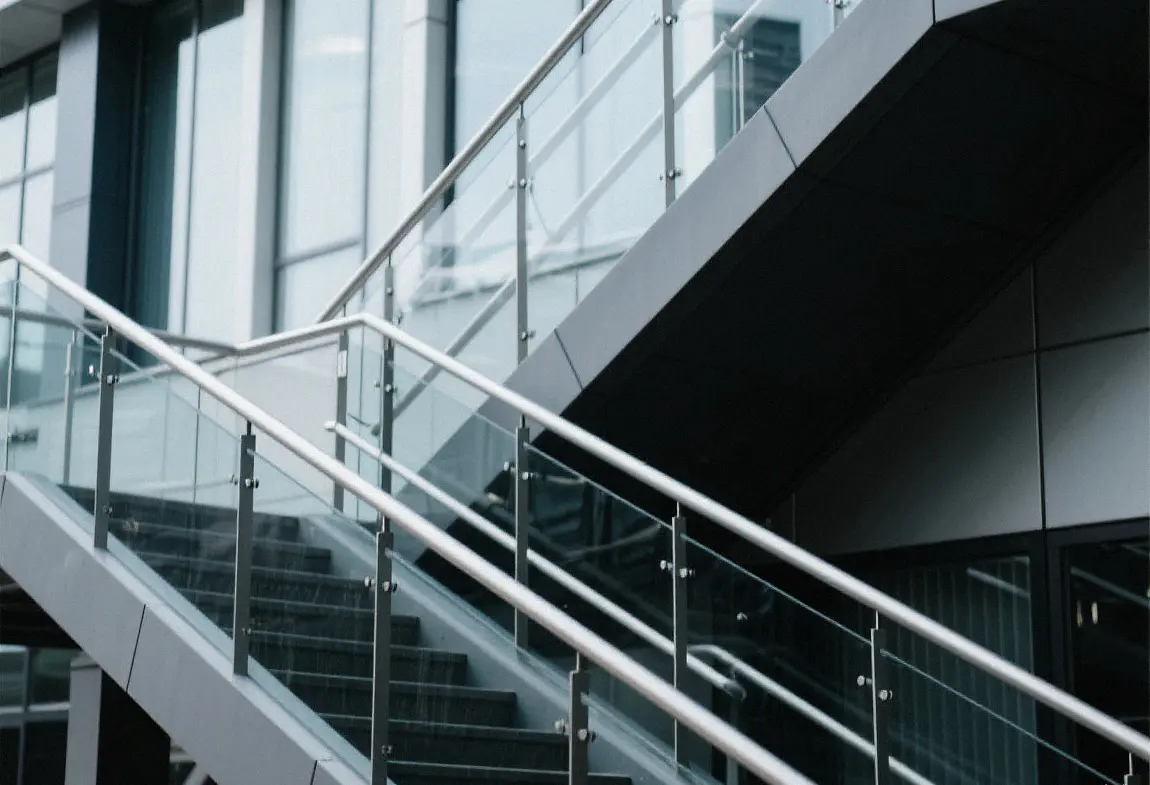 Precision-fabricated stainless steel staircase with a glass handrail in a commercial building.