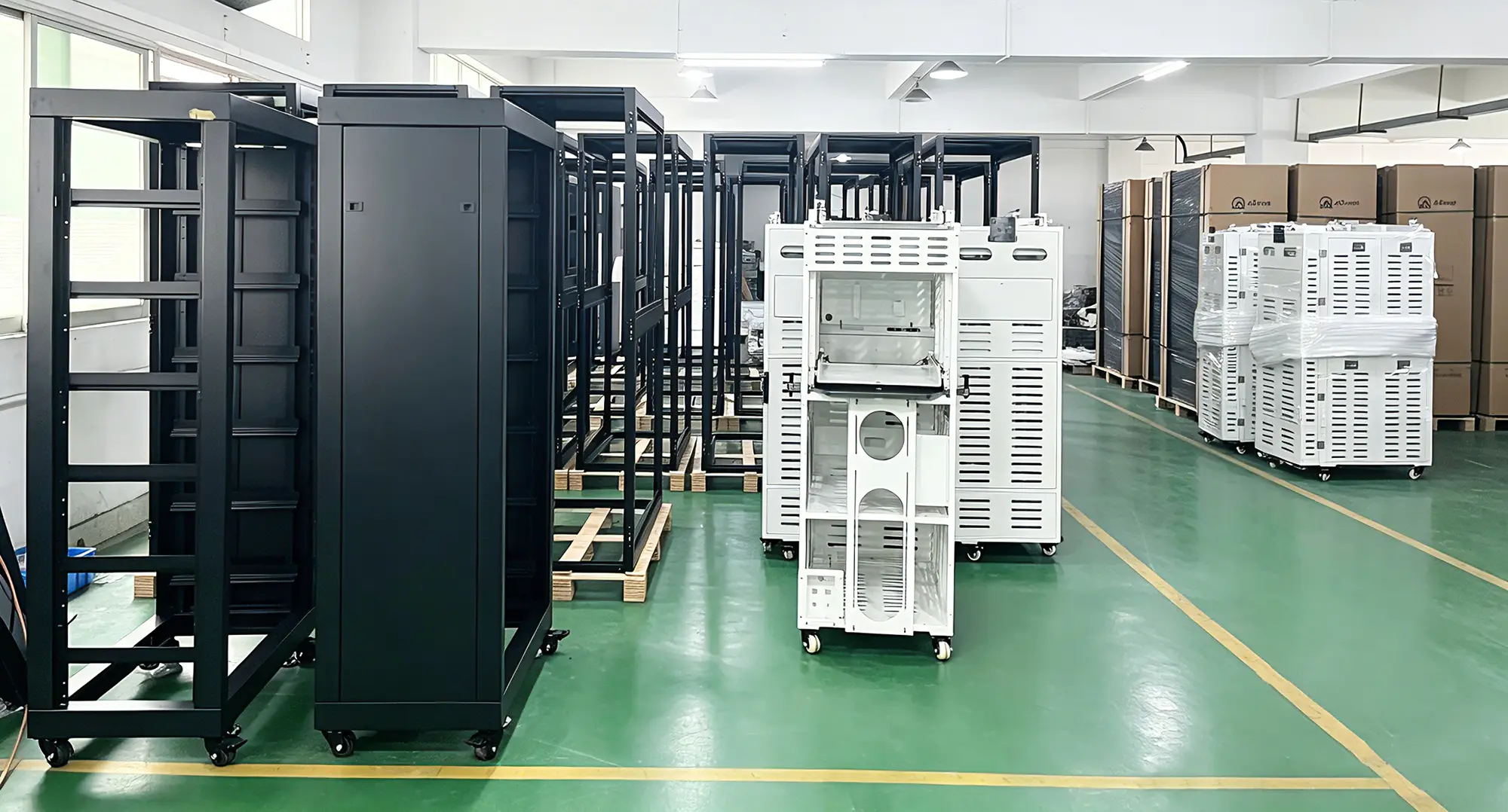 Assembled black and white server enclosures lined up inside sheet metal manufacturing warehouse