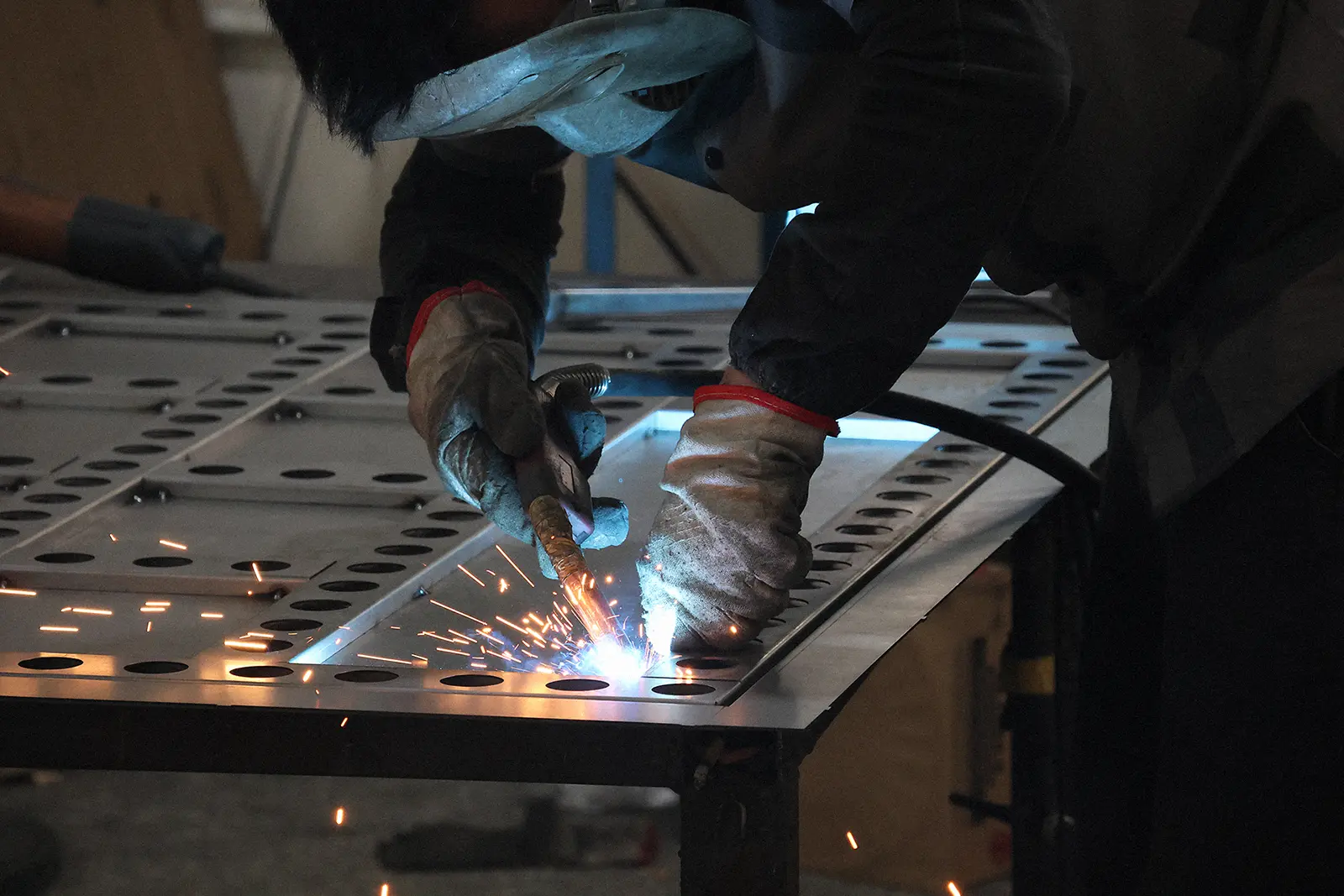 Fabricator MIG-welding an industrial sheet-metal enclosure