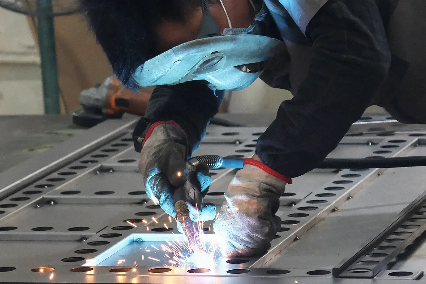 Manual welding operation in sheet metal fabrication workshop